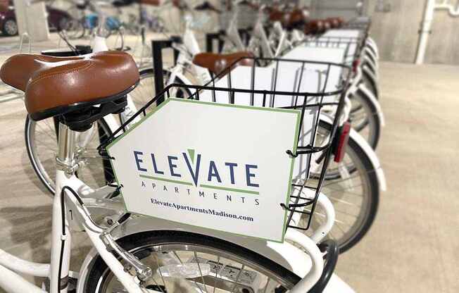 A row of bicycles are parked in a row with a sign that says Elevate Apartments.