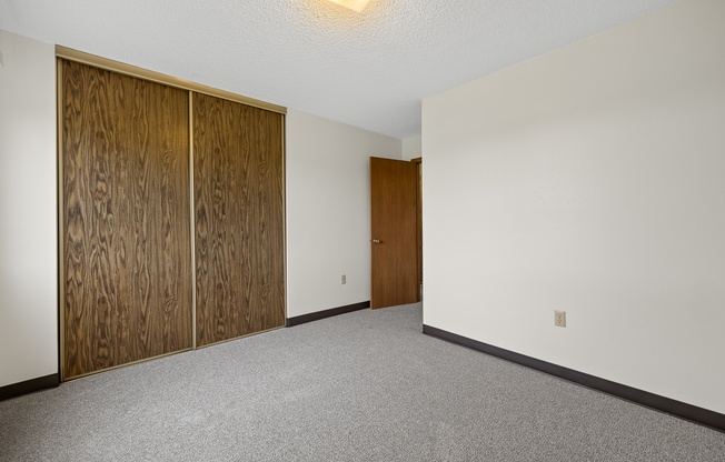 A room with a white wall and a brown door.