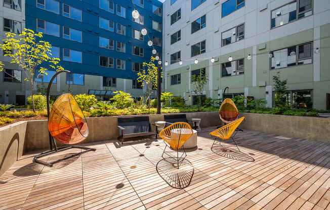 a patio area with chairs and a table in front of an apartment building