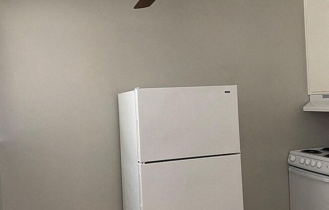 a white refrigerator in a kitchen with a ceiling fan