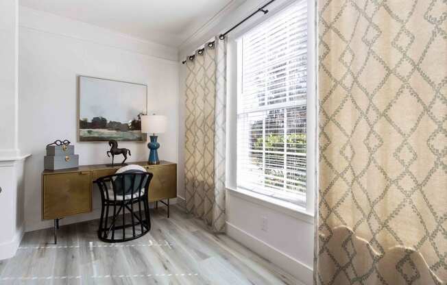 a study with a large window and a desk with a chair