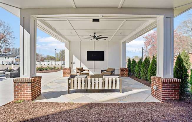A covered patio with a ceiling fan and a flat screen TV.