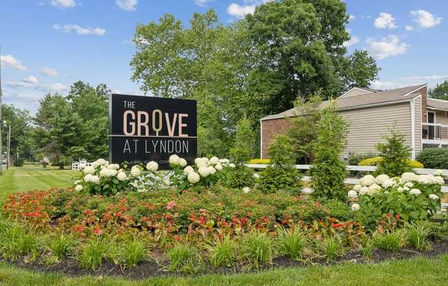 the grove apartments sign in front of flowers and plants