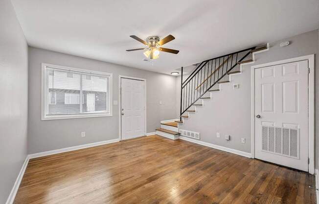 A room with a staircase and a ceiling fan.