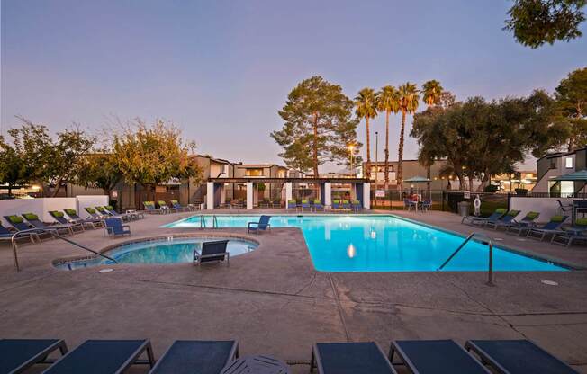 A large outdoor swimming pool surrounded by lounge chairs and palm trees.
