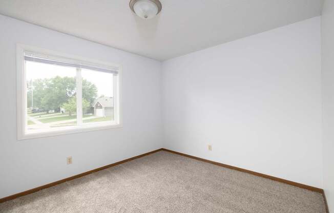 A room with a carpeted floor and a window.