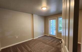 A room with a carpeted floor and a window with blinds.