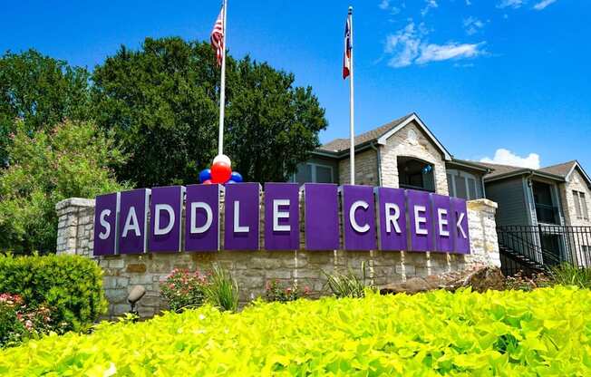 a sign for the saddle creek neighborhood in front of a house