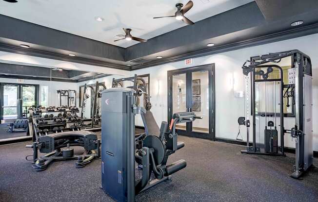 A gym with a variety of equipment including a weight machine, a bench press, and a squat rack.