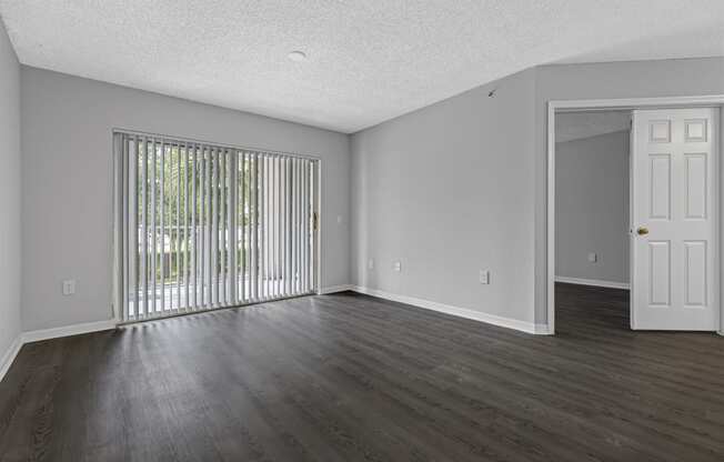 an empty living room with wood floors and a sliding glass door