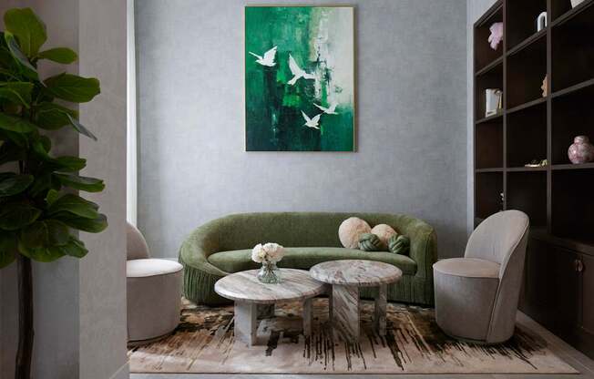 A living room with a green couch, a white chair, and a painting on the wall.