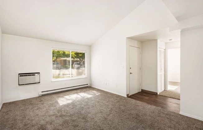 an empty living room with a large window and carpet at Park View Apartments, Wenatchee