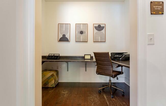 a room with a desk and a chair and paintings on the wall