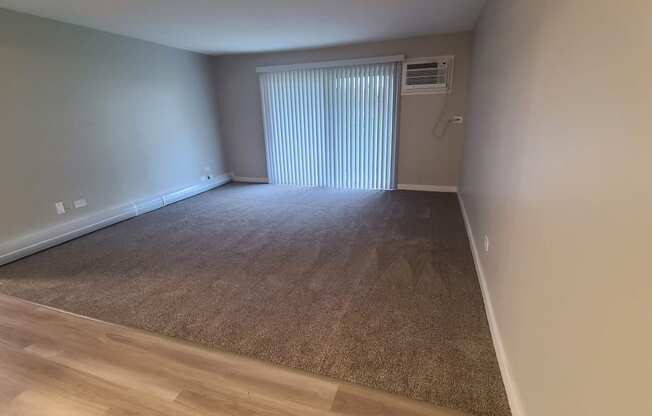 a living room with a window and a carpeted floor