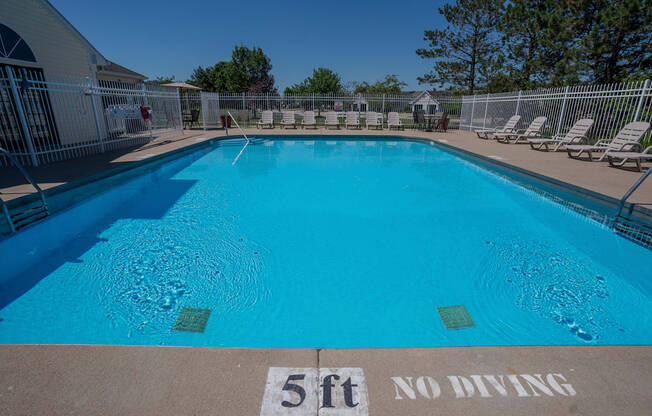 a large pool with chairs and a fence around it