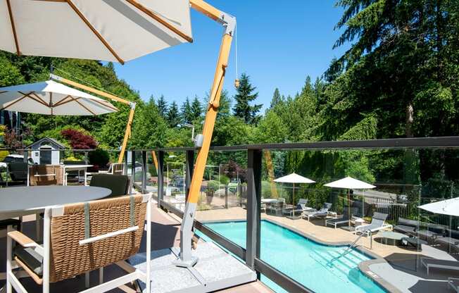 a view of a swimming pool from a patio with tables and chairs