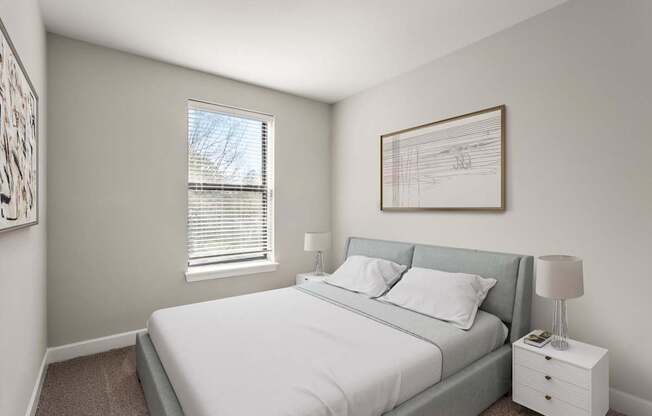 A bedroom with a bed, nightstand, and a framed picture on the wall.