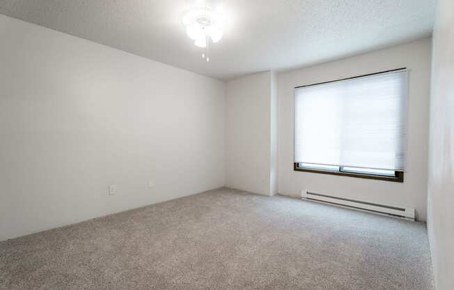 A room with a carpeted floor, a window with blinds, and a ceiling light. at Bristol Ridge, Urbandale, IA, 50322