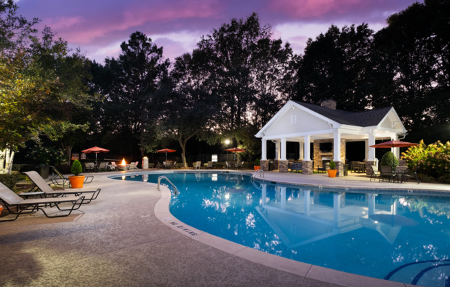 a swimming pool at night in front of a house