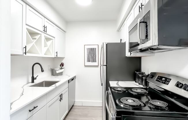 a kitchen with white cabinetry and black appliances  at Park On Canal Apartments, Clinton Twp, MI, 48038