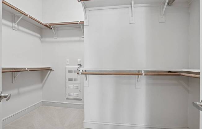 A carpeted walk in closet with white walls and shelves at Knox Heights Apartments in Dallas, TX