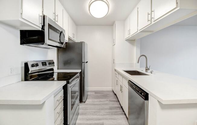 an empty kitchen with white cabinets and stainless steel appliances