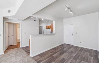 the living room and kitchen of a new home with white walls and wood flooring at St. Augustine Estate, Dallas, TX 75227