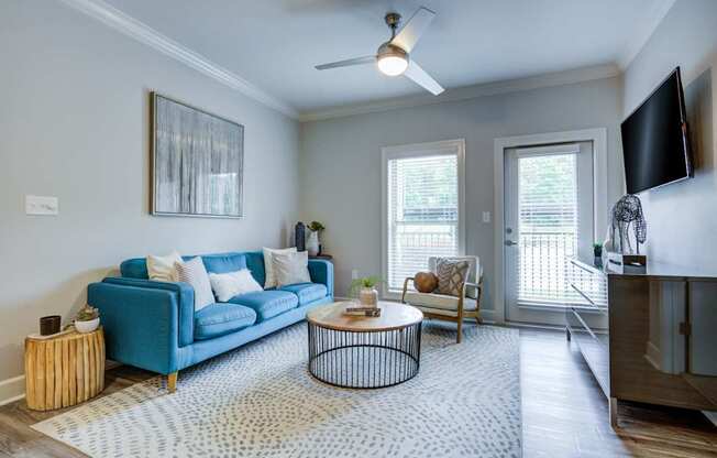 A living room with a blue couch, a coffee table, and a ceiling fan.