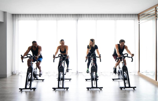 Four people are riding stationary bikes in a row. at Palma, Doral, 33166