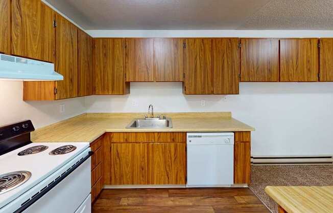 Well-equipped kitchen at Heritage Grove Apartments in Renton WA, with wood-grain cabinetry, full-size refrigerator, and modern finishes.