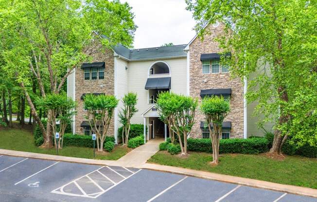 an apartment building with a parking lot and trees