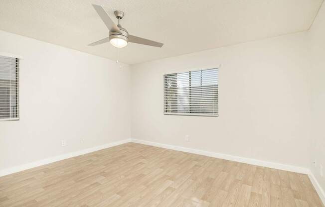 A room with a ceiling fan and wooden flooring.
