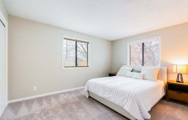 A bedroom with a bed, nightstand, and window.