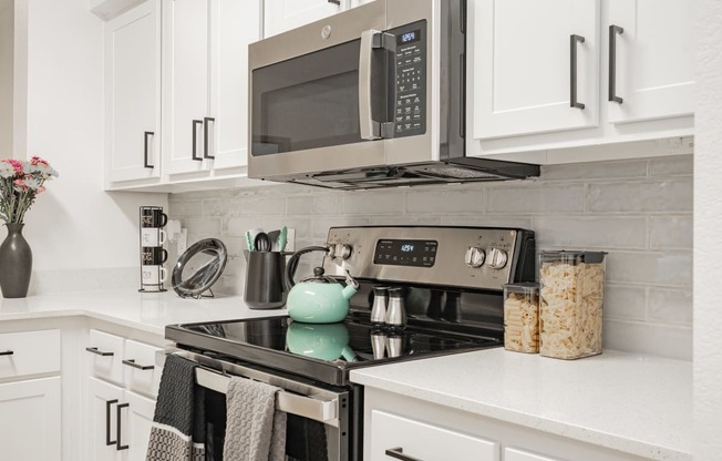 a kitchen with white cabinets and a stove and a microwave
