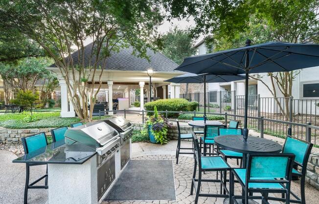 Grill and gather in the shaded outdoor kitchen, featuring built-in gas grills, bar seating, and space to enjoy a meal with neighbors.