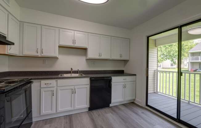 a kitchen with white cabinets and a sliding glass door to a balcony