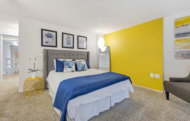 a bedroom with a yellow accent wall and a bed