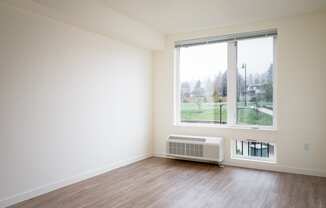 an empty room with a large window and wood floors