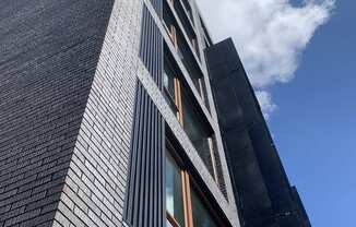 A tall building with a black facade and a large window on the side.