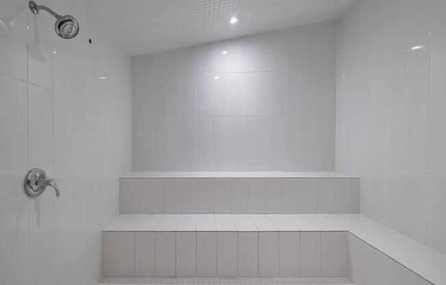 a white bathroom with a shower and white tiles at Altis Grand Suncoast Apartments, Florida