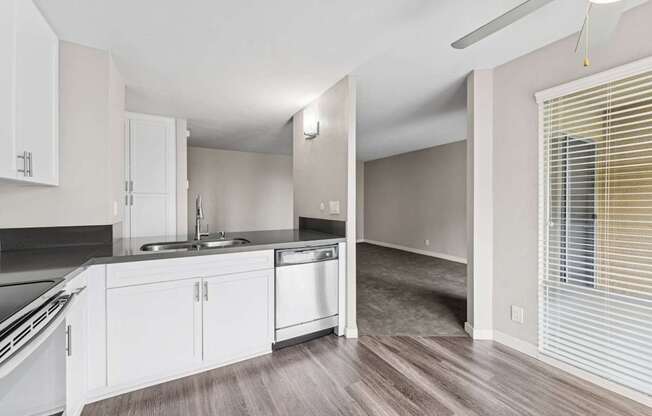 A kitchen with white cabinets and a wooden floor.