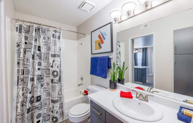 a bathroom with a white sink and toilet next to a bathtub with a shower curtain and