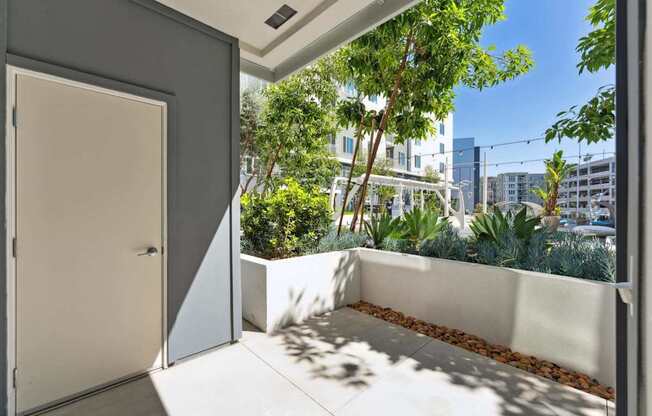 A white door is open to a balcony with a view of a cityscape.