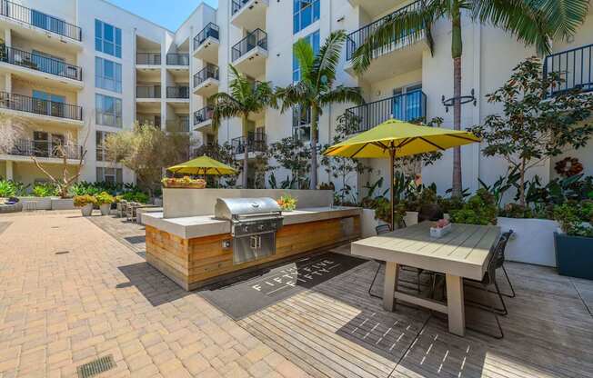 A patio with a table and chairs and a grill.