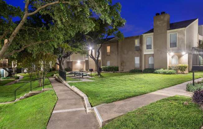 A building with a lawn in front of it is lit up at night.