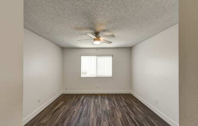 an empty living room with a ceiling fan and a window