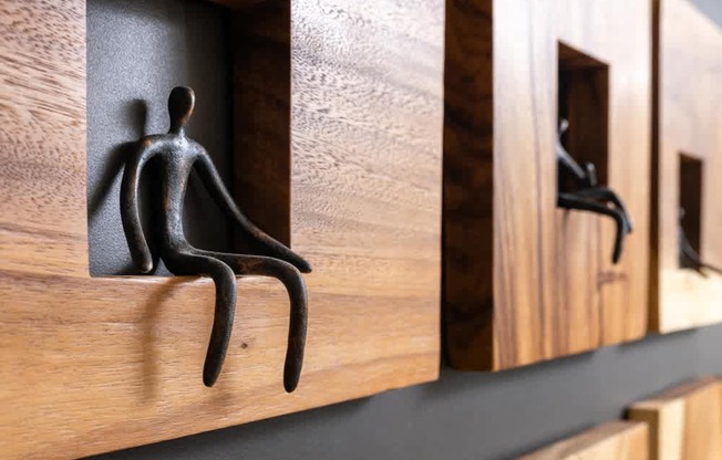 A black sculpture of a person is sitting in a wooden compartment.