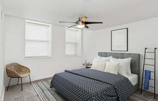 A bedroom with a bed, chair, and a ceiling fan.