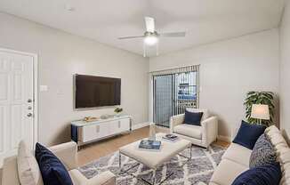 A living room with a white couch, a white coffee table, and a white chair.