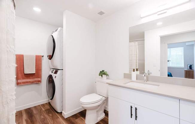 A white bathroom with a toilet, sink, and mirror.